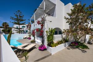 a white house with a swimming pool and flowers at Nissia Beach Apartments & Suites in Kamari