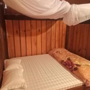 a bed in a wooden room with a canopy at THAI'S Homestay in Kon Rung (1)