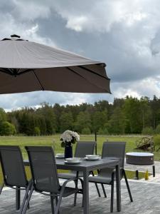 a table with chairs and an umbrella on a patio at Golden House Mazury - kajaki, grill, jacuzzi w cenie noclegu! in Liwa