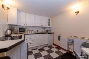 a kitchen with white cabinets and a checkered floor at Harmony Undercroft in North Berwick