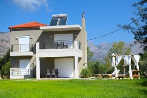 a large house with a balcony and a lawn at paris villas in Mitika
