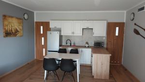 a kitchen with white cabinets and a table and chairs at Apartament na Górce in Mikołajki