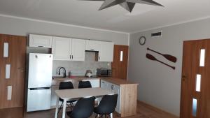 a kitchen with a white refrigerator and a table and chairs at Apartament na Górce in Mikołajki
