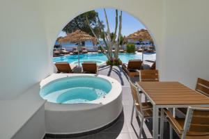 a pool with a hot tub and tables and chairs at Nissia Beach Apartments & Suites in Kamari