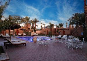 a patio with tables and chairs next to a pool at Zagora Oasis Lodge & Desert Excursions in Zagora