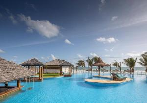 a resort with a large swimming pool with palm trees at The Coral Beach Resort in Trairi
