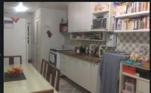 a kitchen with white cabinets and a table with a bowl of fruit at Bela Vista in Rio de Janeiro