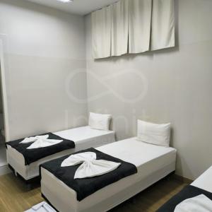 two beds in a small room with white walls at Infinit Hotel Flats in Janaúba +10 photos