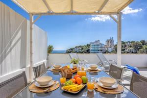 un tavolo con frutta e succo su un balcone di Apartamentos Drac by dracmallorca a Cala Santanyi