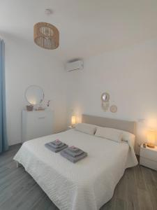 a white bedroom with a bed with two towels on it at Appartamento Regina Margherita in Crotone