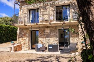 Una casa de piedra con balcón y silla. en Le Petit Mas, en Vence