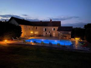 una casa con una gran piscina por la noche en Kimy Villa Lunoterie Futuroscope Piscine et Spa, en Oyré