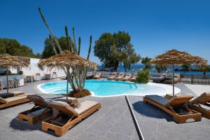 a swimming pool with lounge chairs and umbrellas at Nissia Beach Apartments & Suites in Kamari