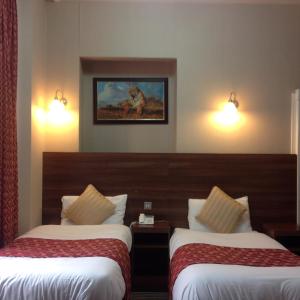 una camera d'albergo con due letti e un dipinto sul muro di Oliver Hotel a Londra