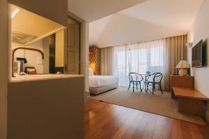 a hotel room with a bedroom and a bed and a table at Torel Saboaria in Porto
