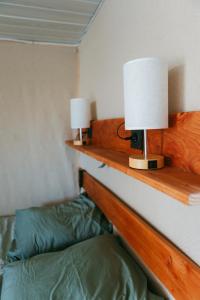 a bedroom with a bed and two lamps on a shelf at La cabane a fleur d eau au cœur de la Camargue in Saint-Gilles