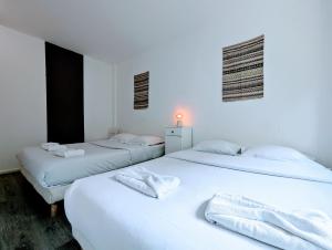 two beds in a room with white walls at Comfortable appart near Paris in Colombes