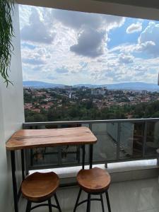 a table and two stools on a balcony with a view at TWIGER HOUSE by WILSON in Kigali