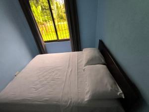 a white bed in a room with a window at La Martha in Sarapiquí