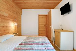 Un dormitorio con una cama, un escritorio y un televisor. en Agritur Montibeller Fravort, en Marter di Roncegno