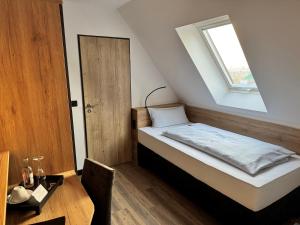 a small bedroom with a bed and a window at Meerzeit Strandhotel in Neuharlingersiel