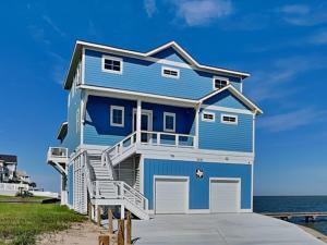 a blue house on the beach next to the ocean at Casa Abide in Galveston