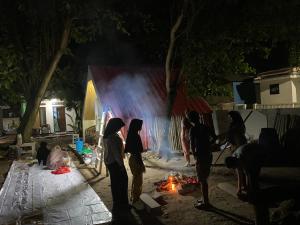 a group of people standing around a fire at night at Kabin Sahara in Pulau Tidung-kecil