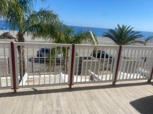 a white fence on a deck with the beach at San Lorenzo Beach in Marina di San Lorenzo