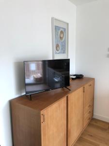 a flat screen tv sitting on top of a wooden cabinet at Les Pins Penchés in Villers-sur-Mer
