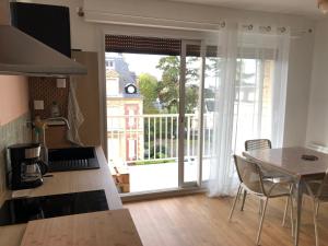 a kitchen with a table and a view of a balcony at Les Pins Penchés in Villers-sur-Mer