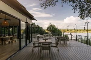 a restaurant with tables and chairs on a deck at Zambezi Sands by Batoka in Victoria Falls