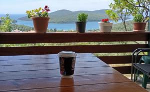 a cup of coffee sitting on a wooden table with potted plants at Charoula's Apartments in Syvota