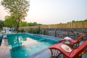 ein Pool mit einer Bank und zwei Stühlen daneben in der Unterkunft ELIVAAS 3 BHK Amber Villa With Pvt Pool, Game Room & Studio Rooms in Dhauj + 75 Fotos