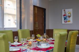 ein Tisch mit grünen Stühlen und ein Tisch mit Weingläsern in der Unterkunft ELIVAAS 3 BHK Amber Villa With Pvt Pool, Game Room & Studio Rooms in Dhauj