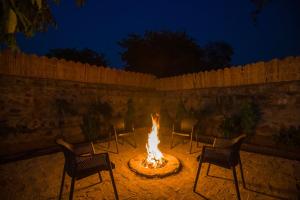 eine Feuerstelle auf einer Terrasse mit Stühlen in der Unterkunft ELIVAAS 3 BHK Amber Villa With Pvt Pool, Game Room & Studio Rooms in Dhauj