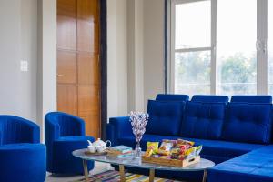 ein Wohnzimmer mit einem blauen Sofa und blauen Stühlen in der Unterkunft ELIVAAS 3 BHK Amber Villa With Pvt Pool, Game Room & Studio Rooms in Dhauj