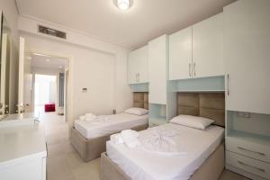 two beds in a room with white cabinets at Luxury Sea View Apartments in Sarandë