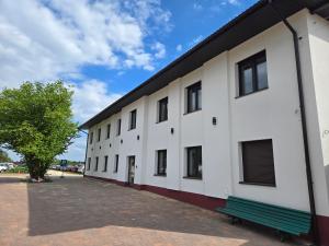 ein weißes Gebäude mit einer grünen Bank daneben in der Unterkunft VUELO - shuttle gratis in Pyrzowice