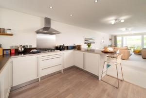 a kitchen with white cabinets and a living room at 6 Bluestone Point in Mortehoe