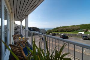 a balcony with a table and chairs and a view of the ocean at 6 Bluestone Point in Mortehoe