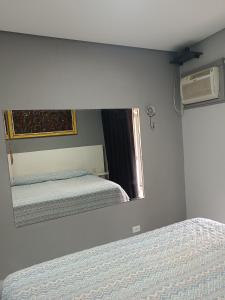 ein Schlafzimmer mit zwei Betten und einem Spiegel in der Unterkunft Maresias chalé in Maresias