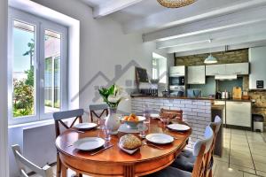 a kitchen and dining room with a wooden table and chairs at LocaLise - M26B - Les Belles Âmes - Maison rénovée avec jardin entièrement clos - place de parking sur le terrain - wifi inclus - draps inclus - animaux bienvenus in Le Guilvinec