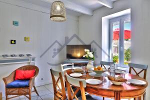 a dining room with a wooden table and chairs at LocaLise - M26B - Les Belles Âmes - Maison rénovée avec jardin entièrement clos - place de parking sur le terrain - wifi inclus - draps inclus - animaux bienvenus in Le Guilvinec