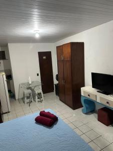 a room with a bed and a tv and a table at Um quarto completo in João Pessoa