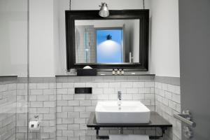 ein weißes Badezimmer mit einem Waschbecken und einem Spiegel in der Unterkunft Staytion Urban City Hotel Mannheim in Mannheim