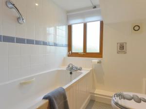 une salle de bain blanche avec une baignoire et une fenêtre dans l'établissement Lavender Cottage, à Okehampton 12 autres photos