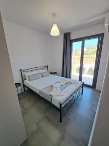 a bedroom with a bed and a large window at Terracotta Sunset Naxos in Galanádhon
