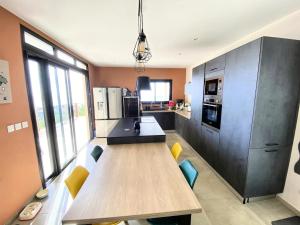 a kitchen with a wooden table and some chairs at Villa Perle de l'ouest - piscine et vue mer 180 sur la baie de St-Paul in Saint-Paul