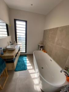 a bathroom with a large white tub and a sink at Villa Perle de l'ouest - piscine et vue mer 180 sur la baie de St-Paul in Saint-Paul