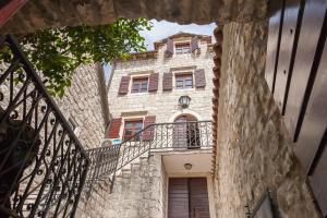 Edificio de piedra antiguo con balcón y escalera en Villa & Apartments Perasto en Perast